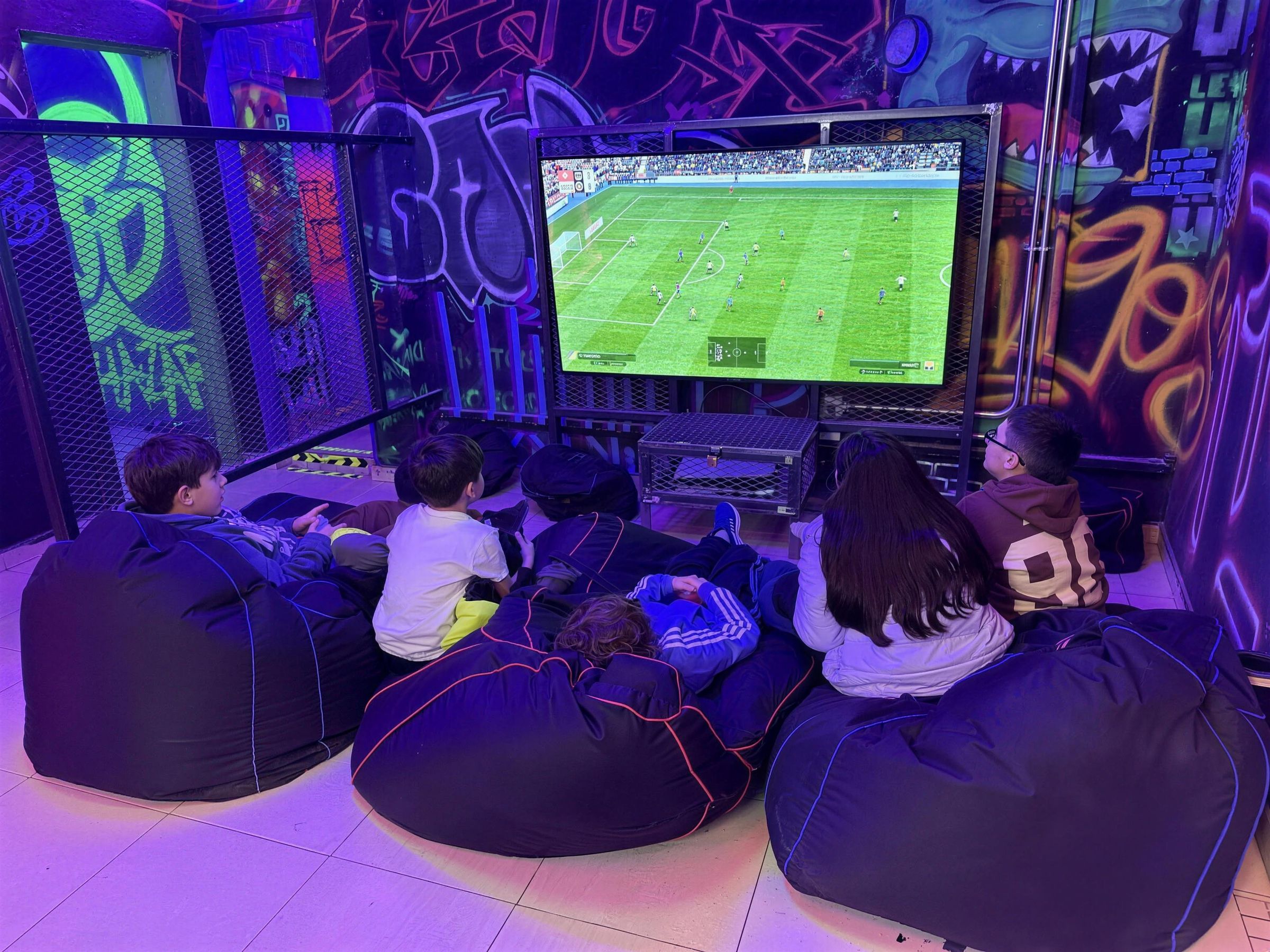 Chicos jugando al FIFA en la pantalla grande de Bunker Stone